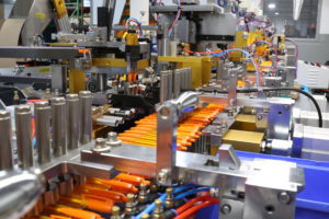 factory machines with an assembly of orange pens